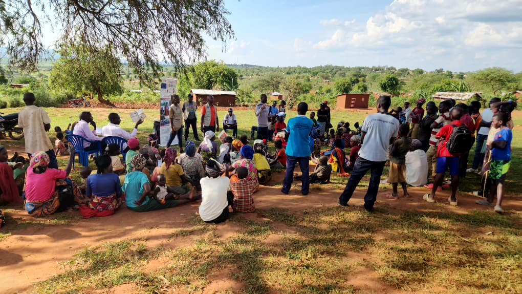 Community awareness session with women and children under a tree in Nakivale